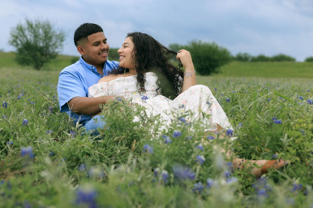 Couple session in a blue bonnet field while husband is holding wife close.