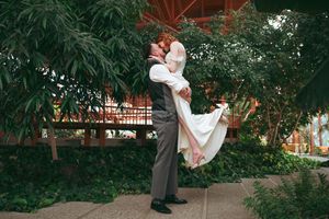 A couple in wedding attire shares a romantic embrace in a lush garden setting during their special day.