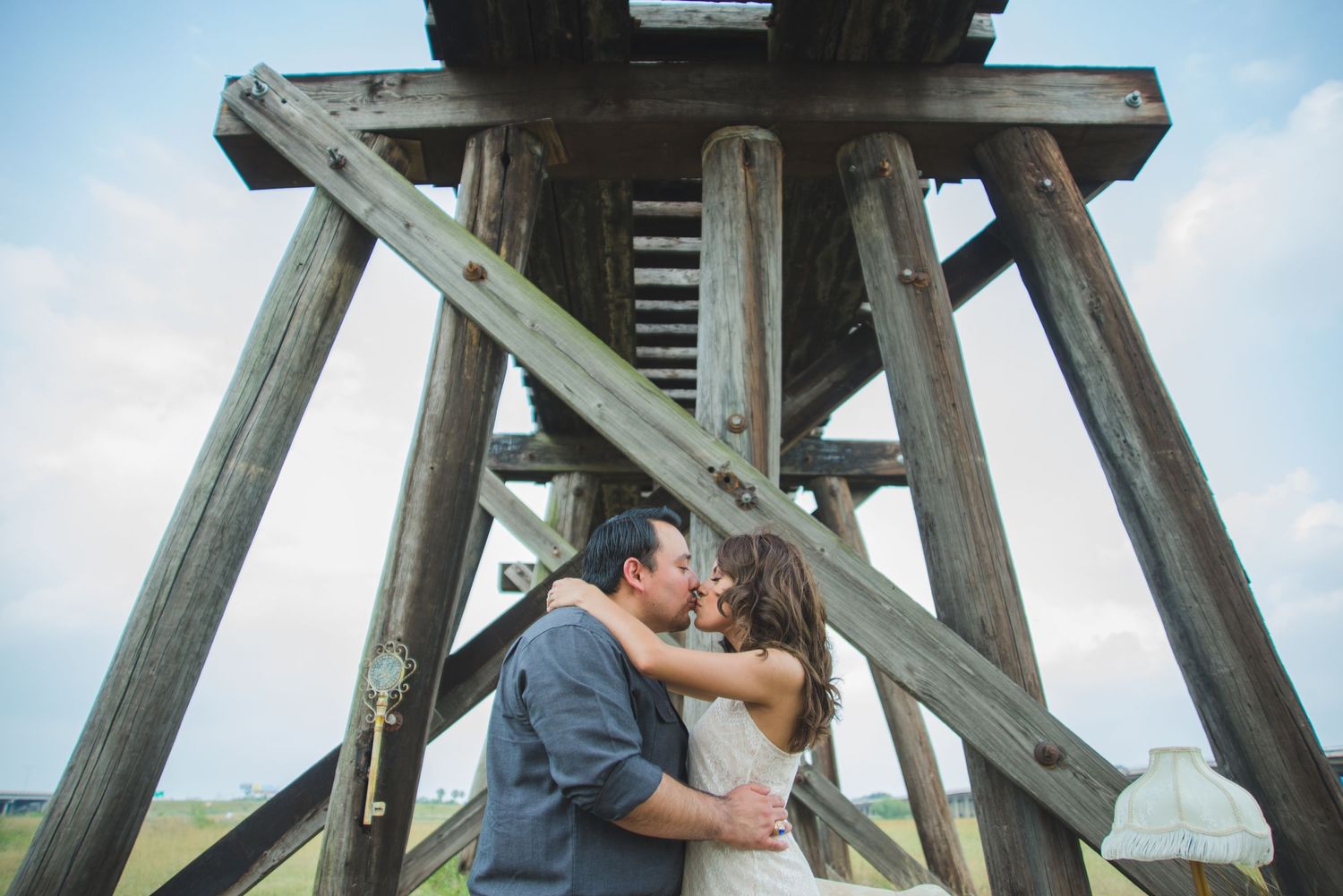 Romantic scene beneath wooden pier structure with soft lighting and coastal backdrop.