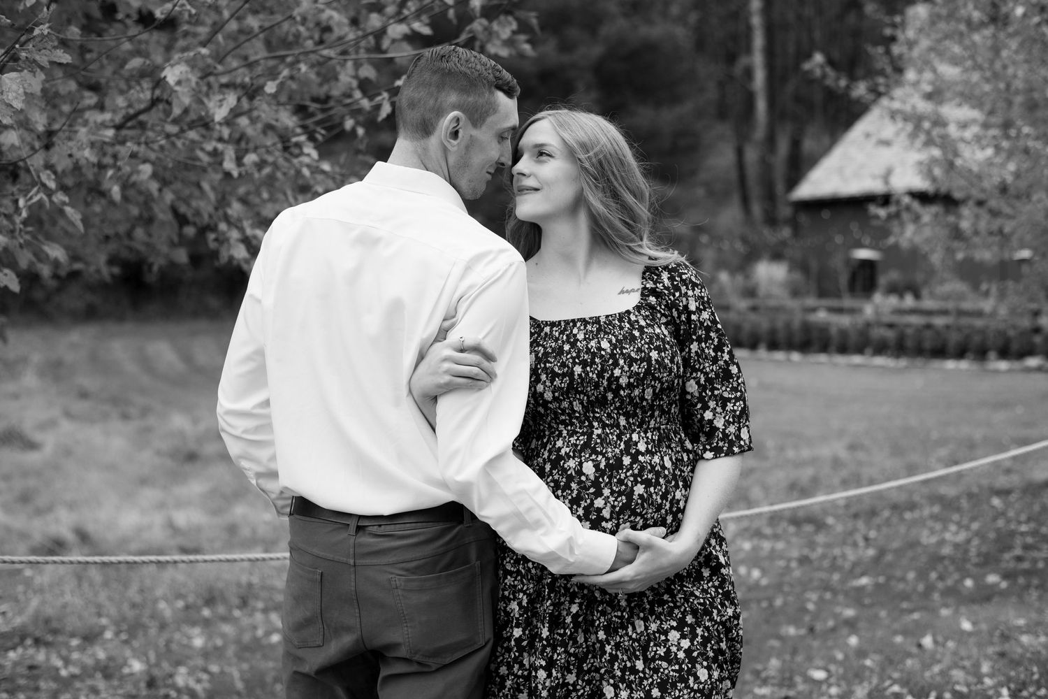 Black and white portrait of a couple sharing an intimate moment in a garden setting.