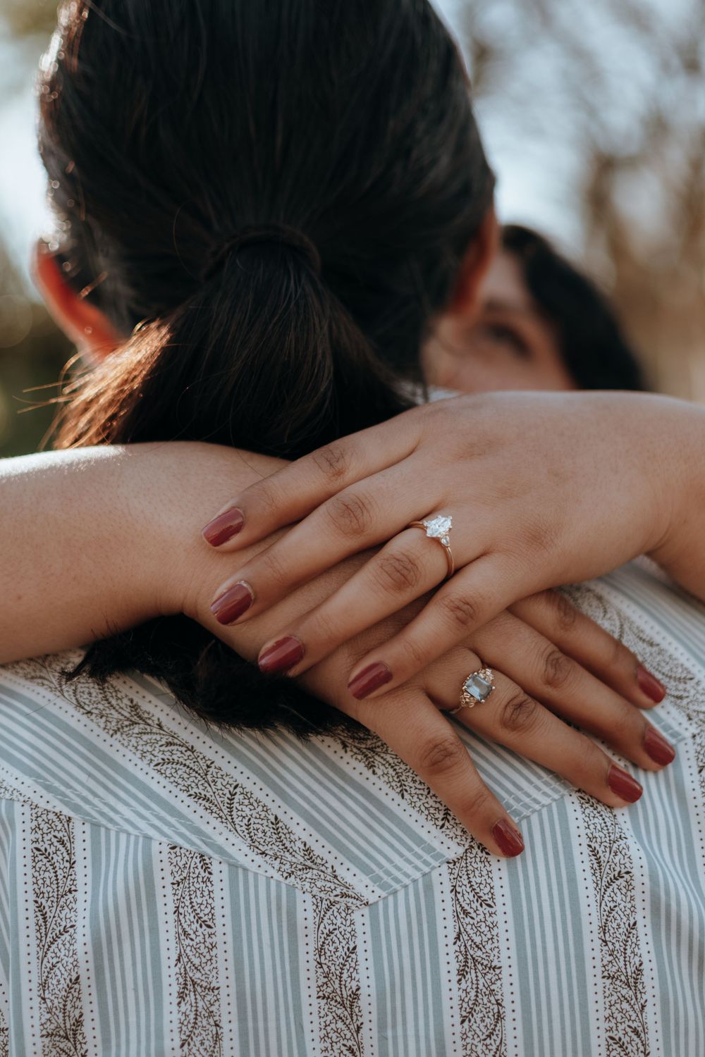 Close-up of hands with engagement rings embracing during an intimate moment.
