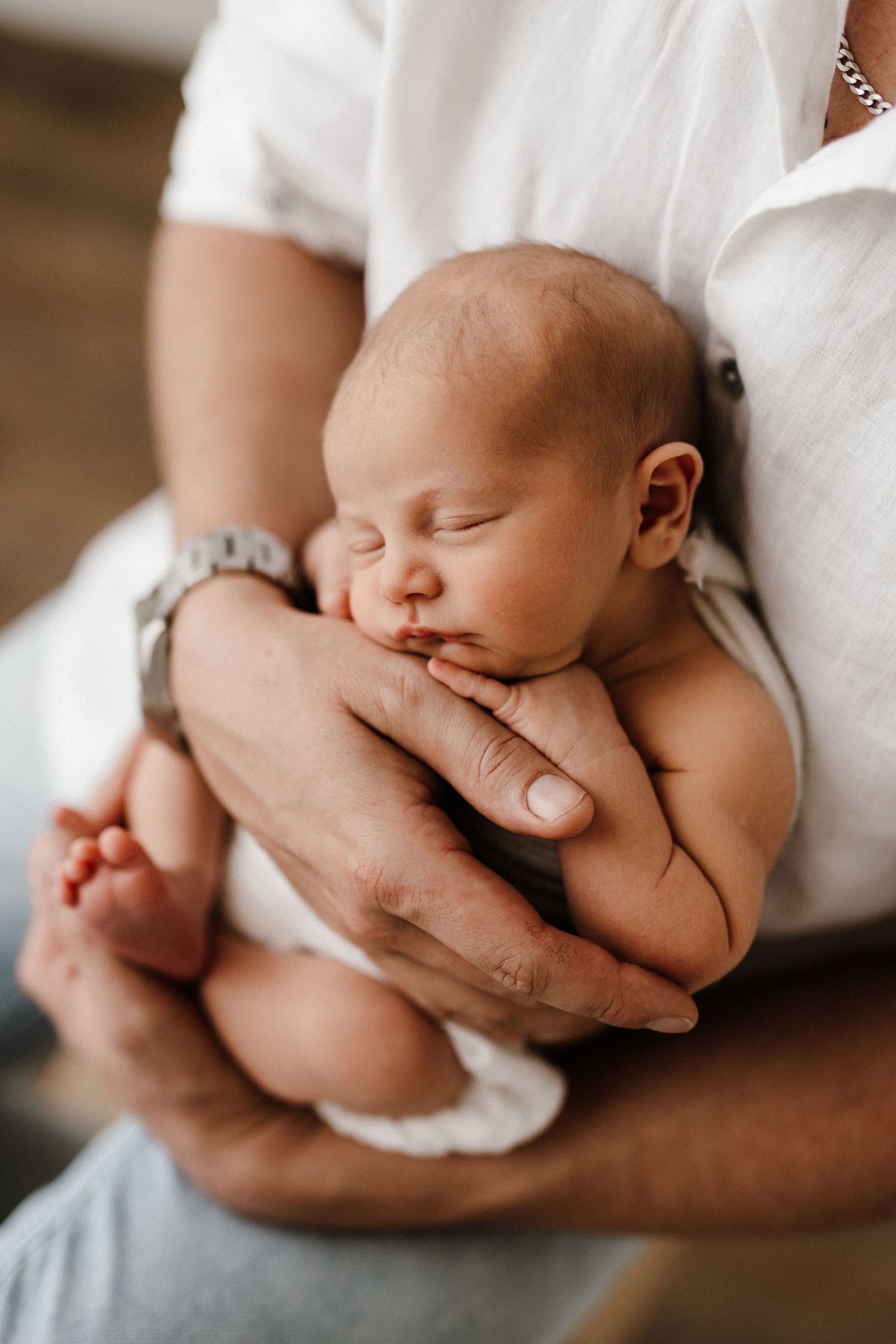 Close-up shots of a sleeping newborn being gently cradled in hands.