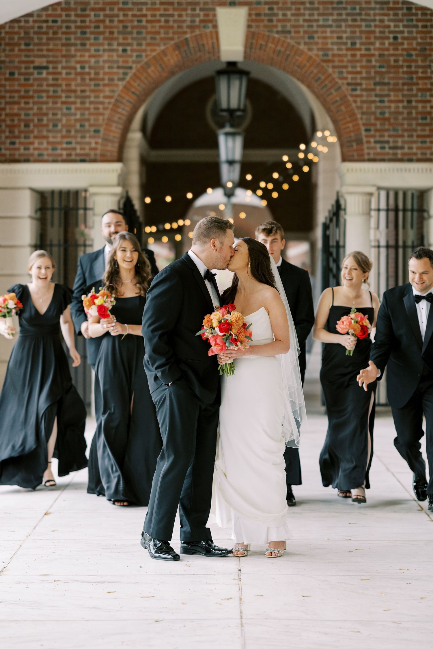A romantic wedding moment with a colorful bouquet of roses and dahlias under an elegant archway with twinkling lights at Hall of Springs.