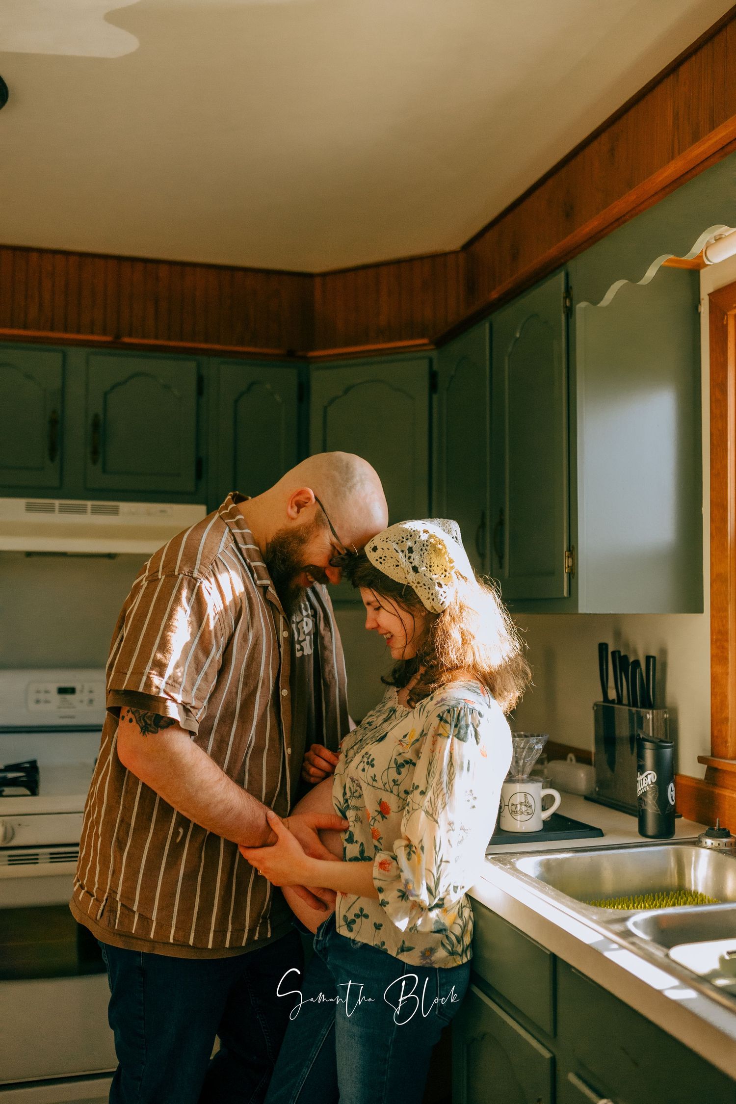 Romantic couple sharing intimate moment in kitchen with green cabinets.