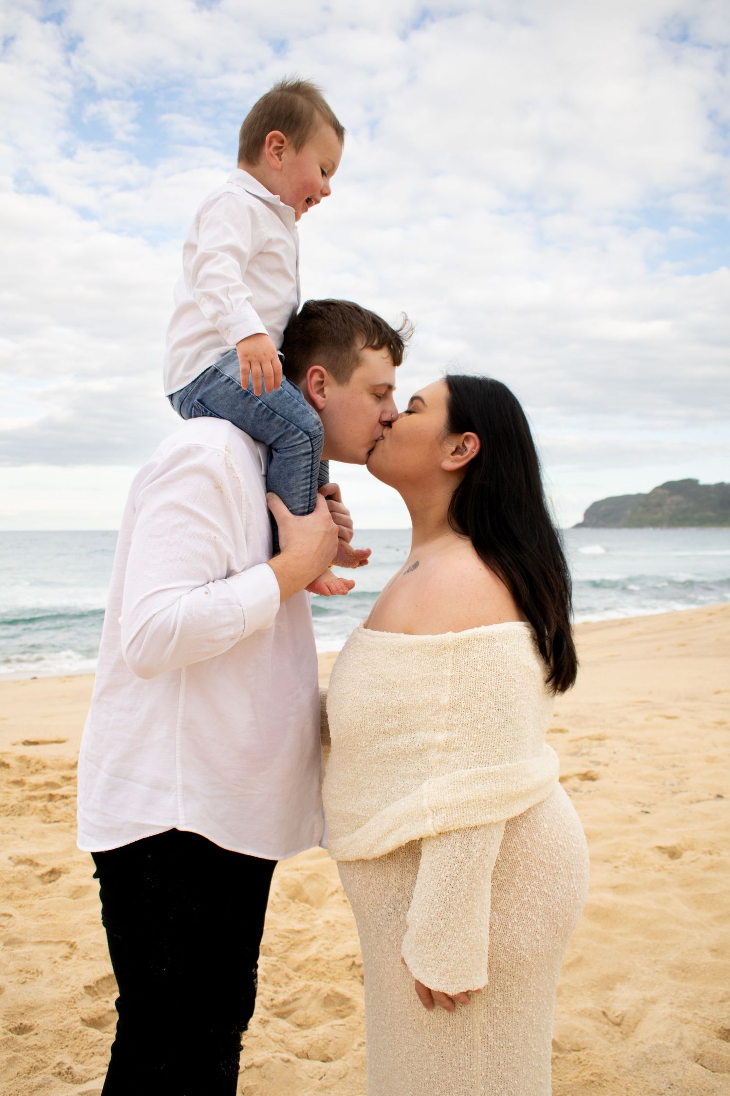 Newcastle maternity photographer capturing mother-to-be at the beach with partner and toddler