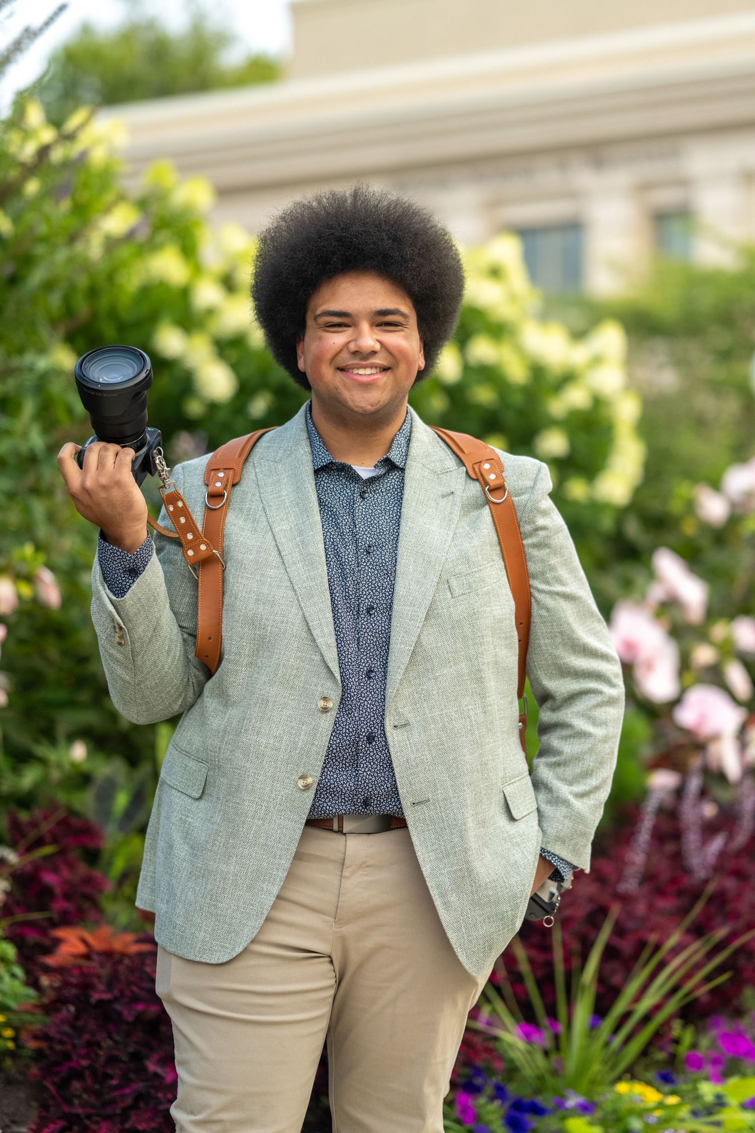 Portrait of the lead wedding photographer taken on a rustic garden path surrounded by natural foliage and stone walls.