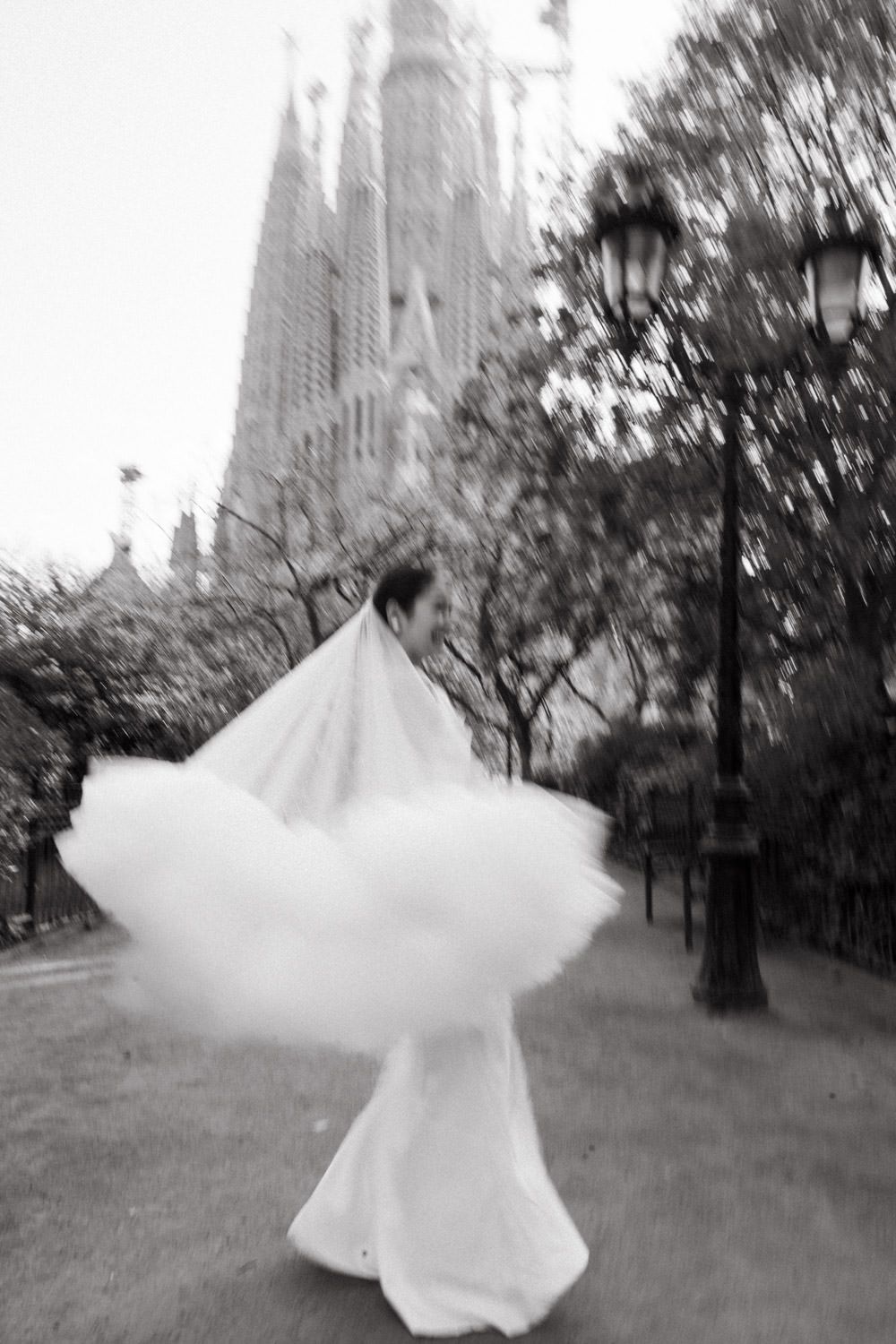 A flowing white wedding dress twirls in motion against the backdrop of Sagrada Familia.