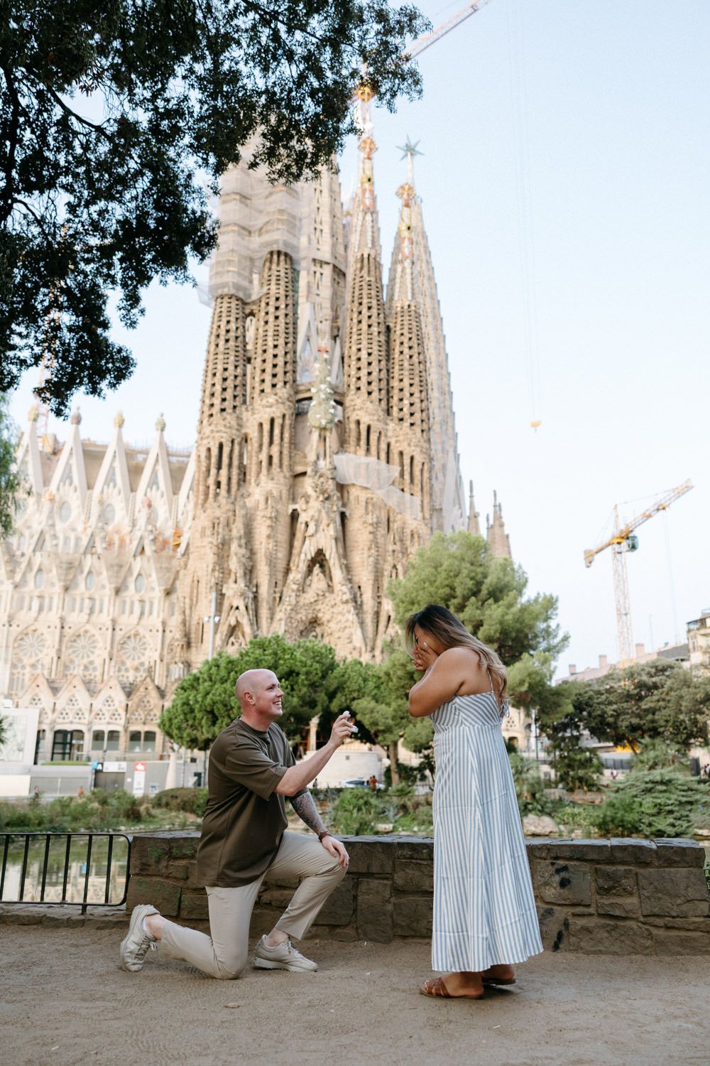Romantic proposal moment in front of Barcelona's iconic Sagrada Familia cathedral.