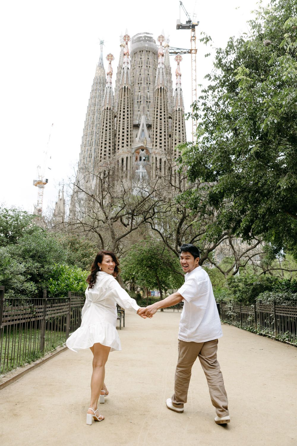 Playful couple dances together near the Sagrada Familia cathedral in Barcelona.