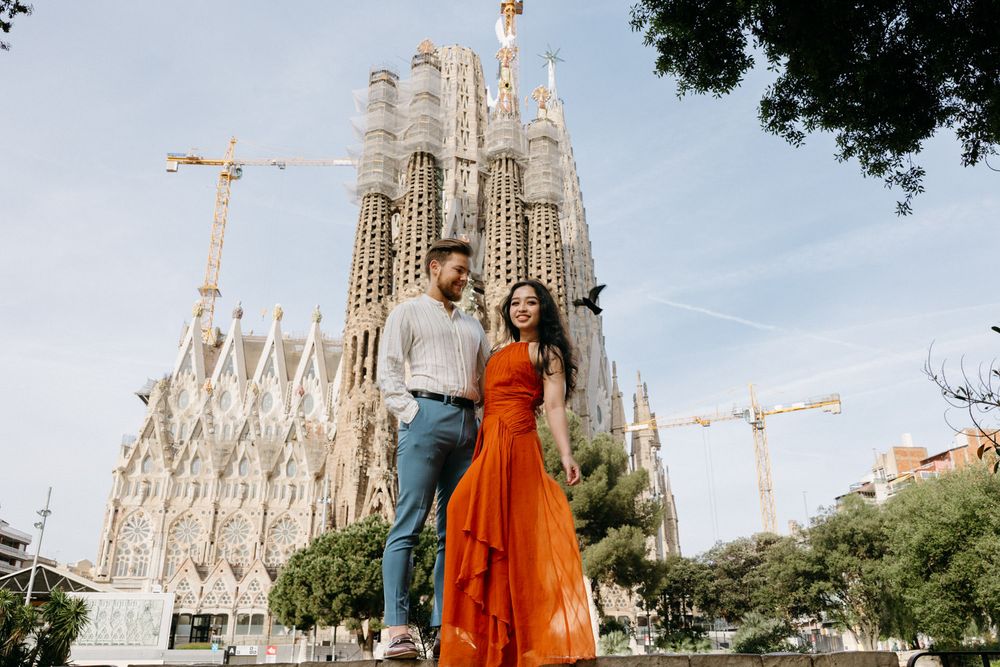 Couple shares tender moment in front of Barcelona's iconic Sagrada Familia cathedral.