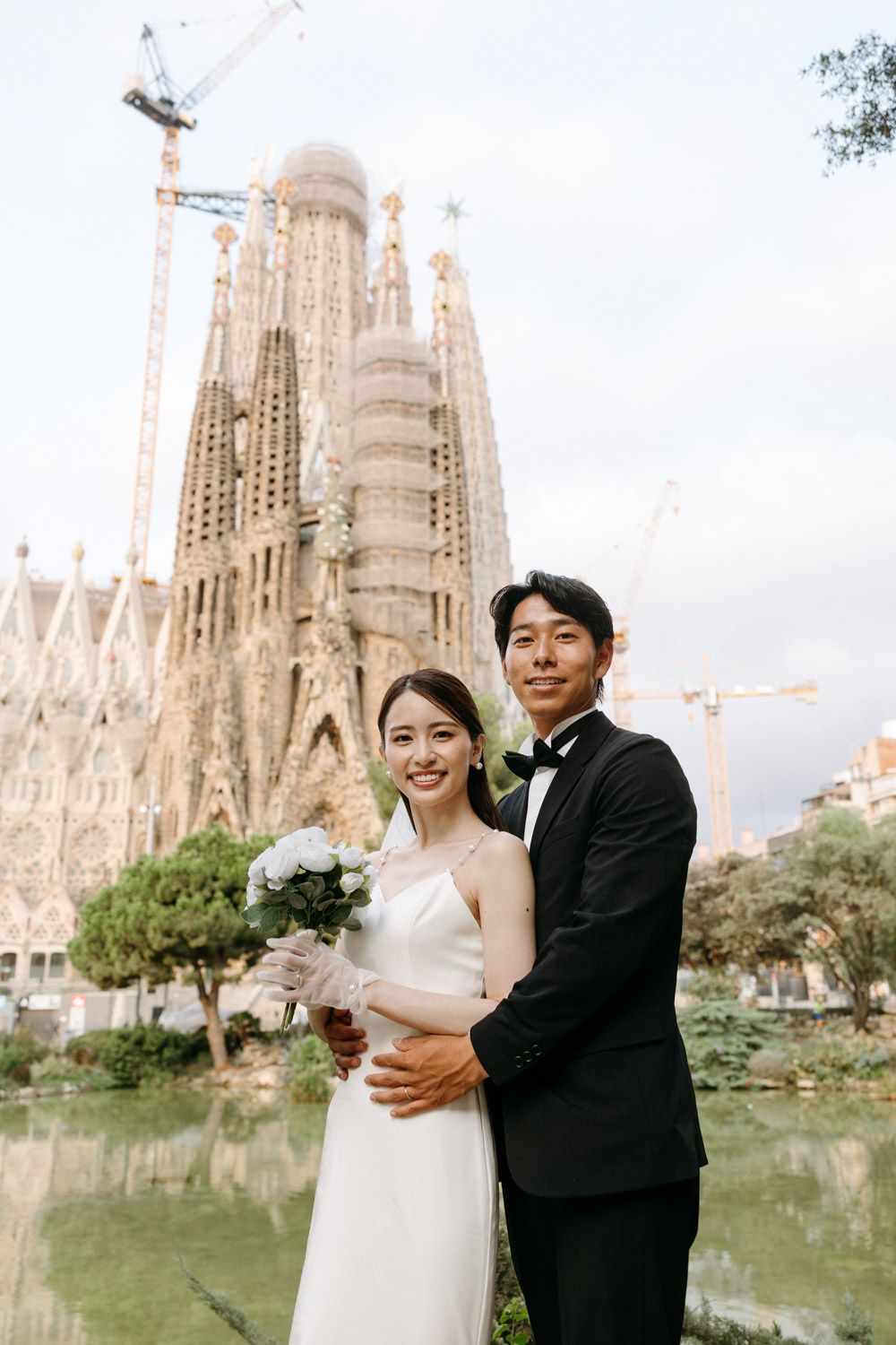 Newlyweds embrace in front of the majestic Sagrada Familia cathedral.