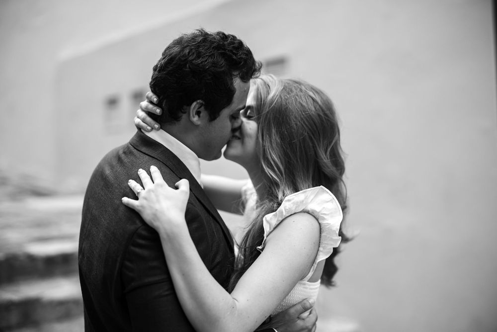 A romantic black and white photo of a couple embracing, inches away from a kiss in tender lighting.