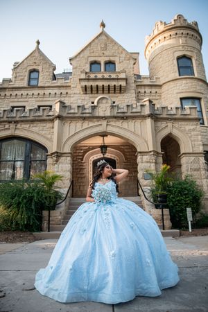 Light blue ballgown photographed in front of a grand stone castle entrance.
