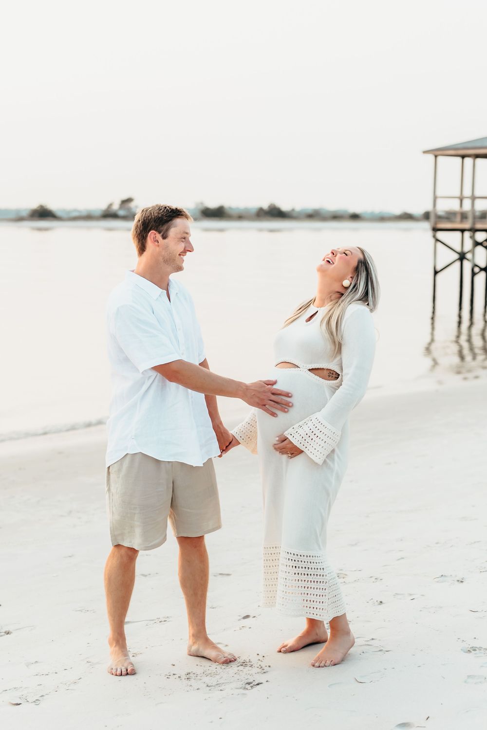 Barefoot couple enjoys playful moment during beach maternity photoshoot. Sunset Wrightsville beach wilmington nc