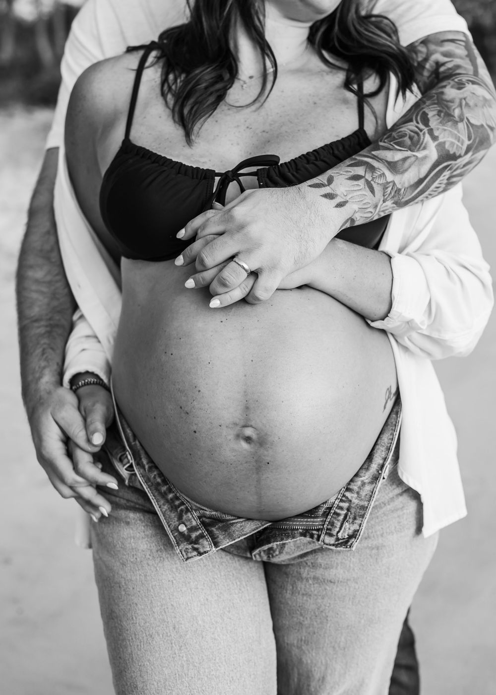 Black and white intimate maternity photo showing hands cradling belly.