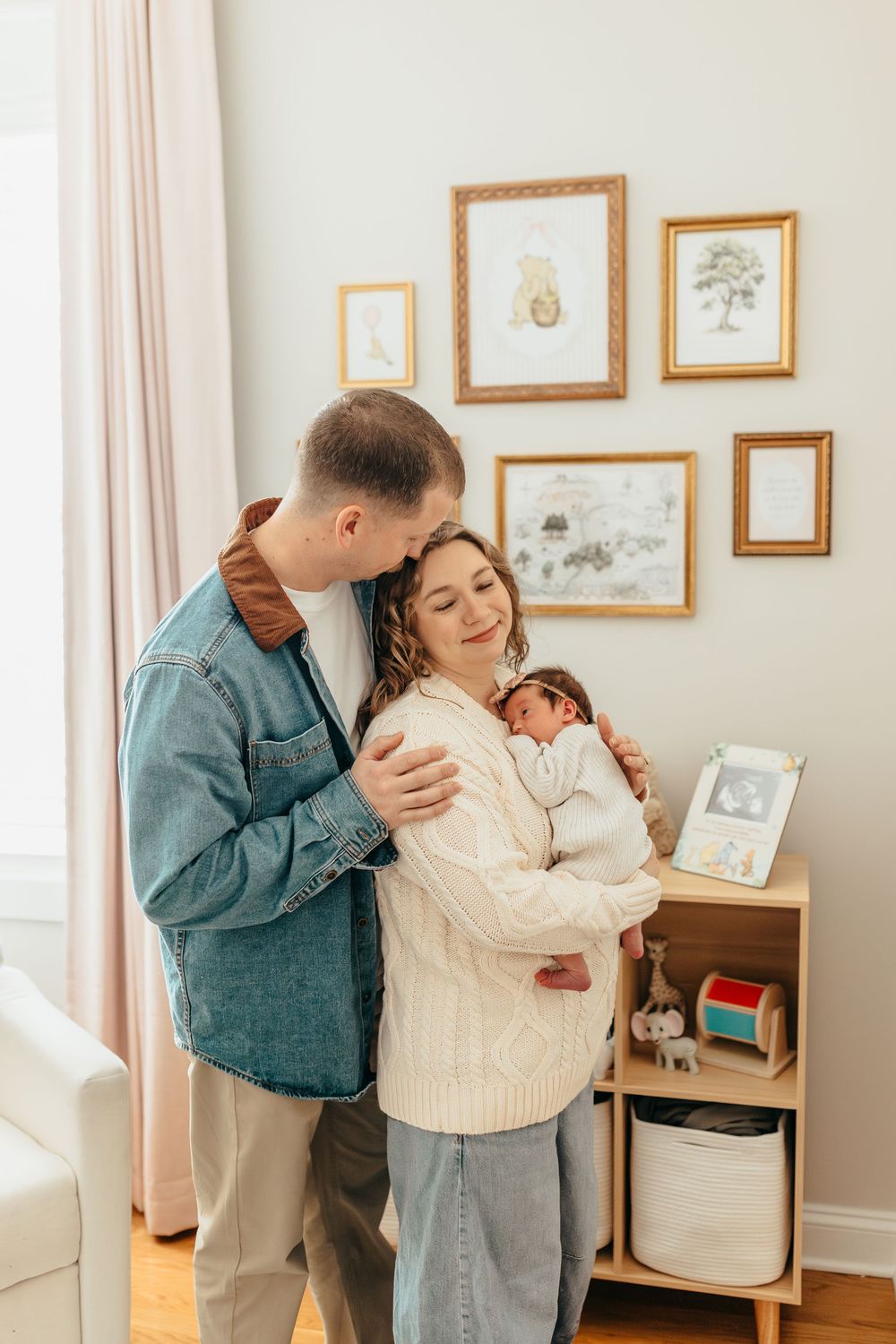 A couple embraces tenderly in a cozy room with framed artwork on the wall, creating an intimate moment.