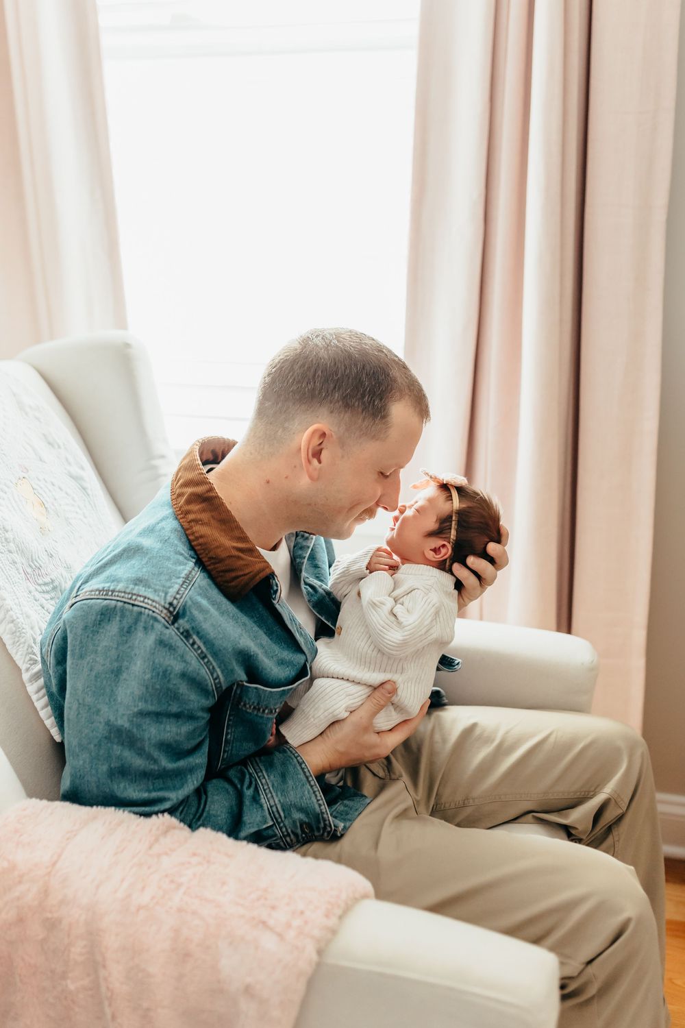Parent and baby share tender moment on cream colored couch in living room.