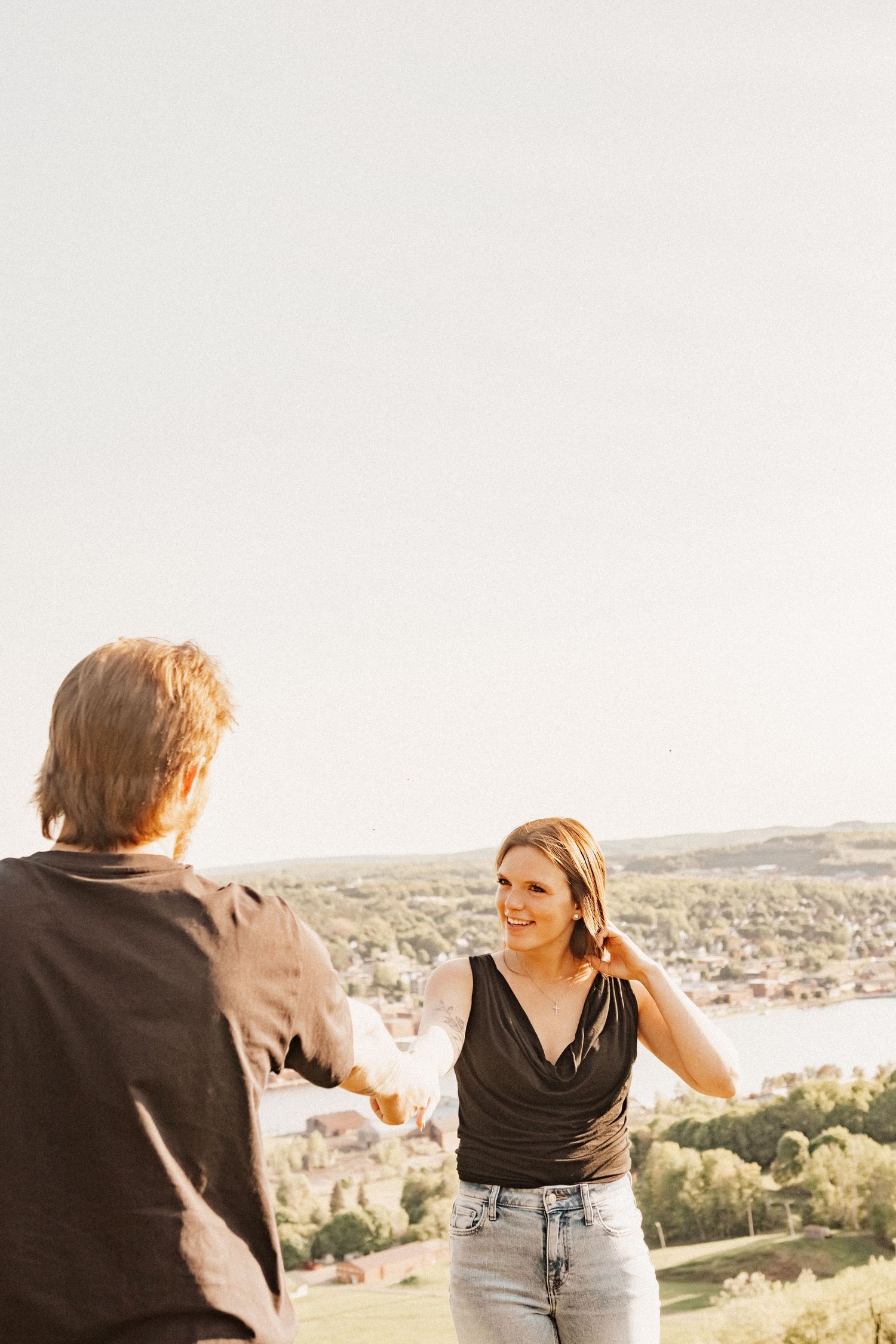 Two people dancing together on a hilltop overlooking a scenic valley landscape.