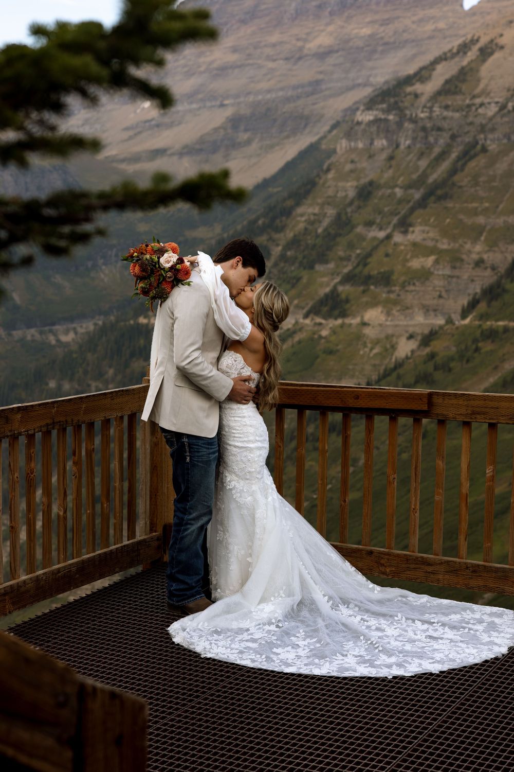 A romantic moment captured at a scenic mountain overlook with a flowing white wedding dress and dramatic landscape view.