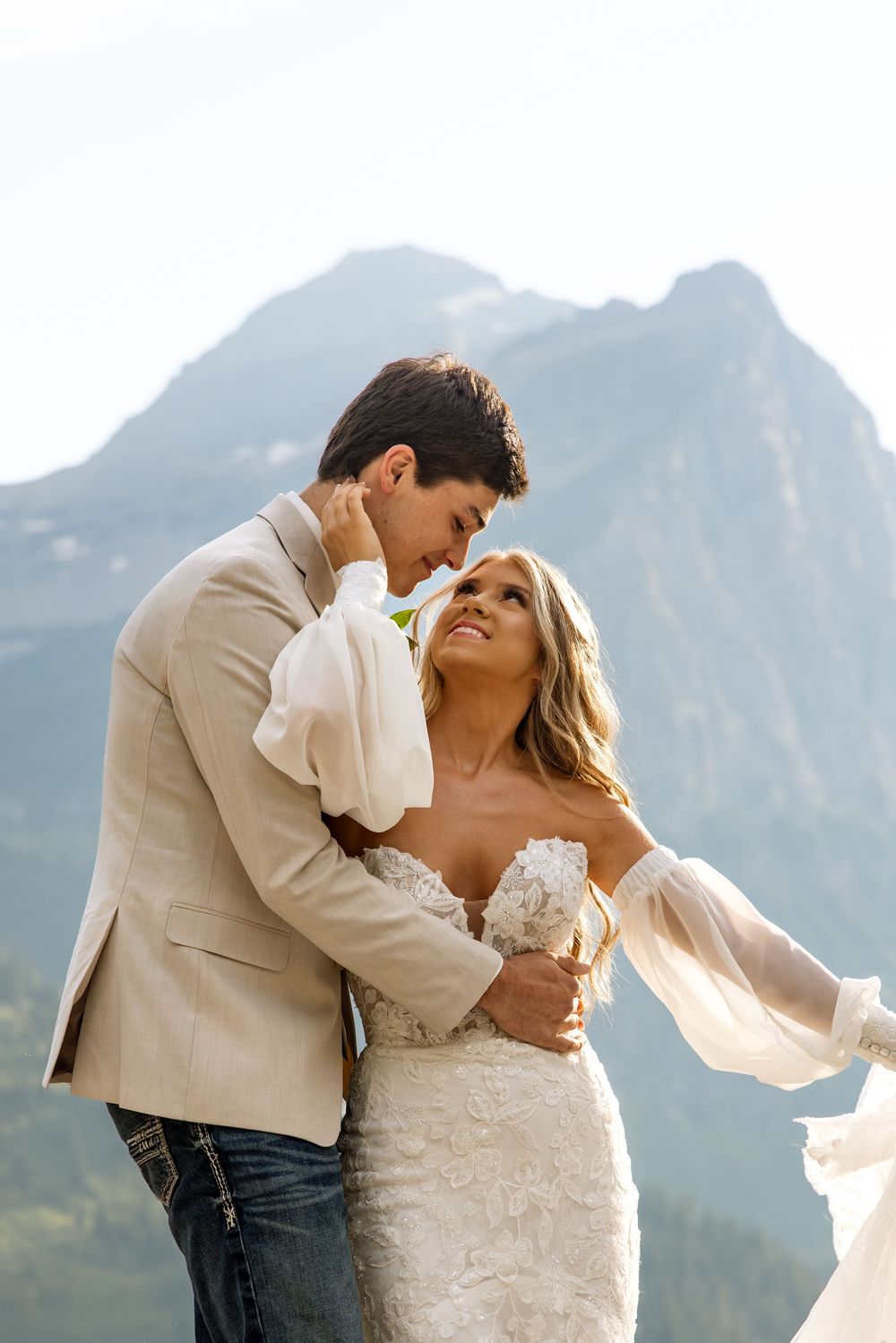 A romantic wedding couple embraces against a dramatic mountain backdrop on their special day.