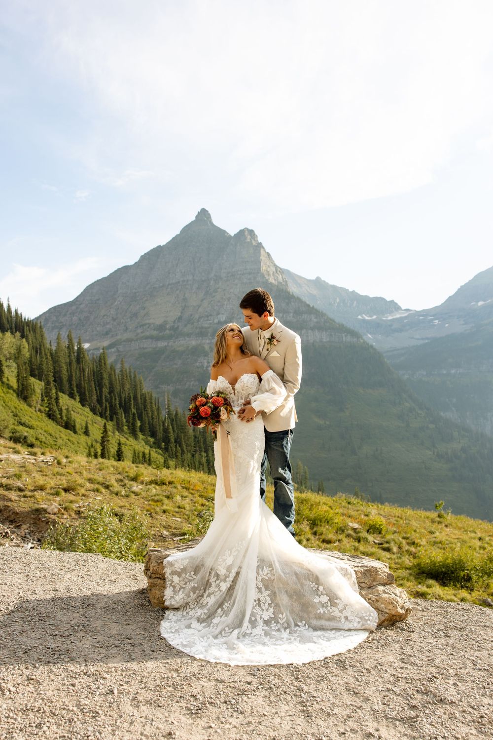 Stunning mountain wedding photo with dramatic peaks and forest backdrop as couple shares intimate moment.