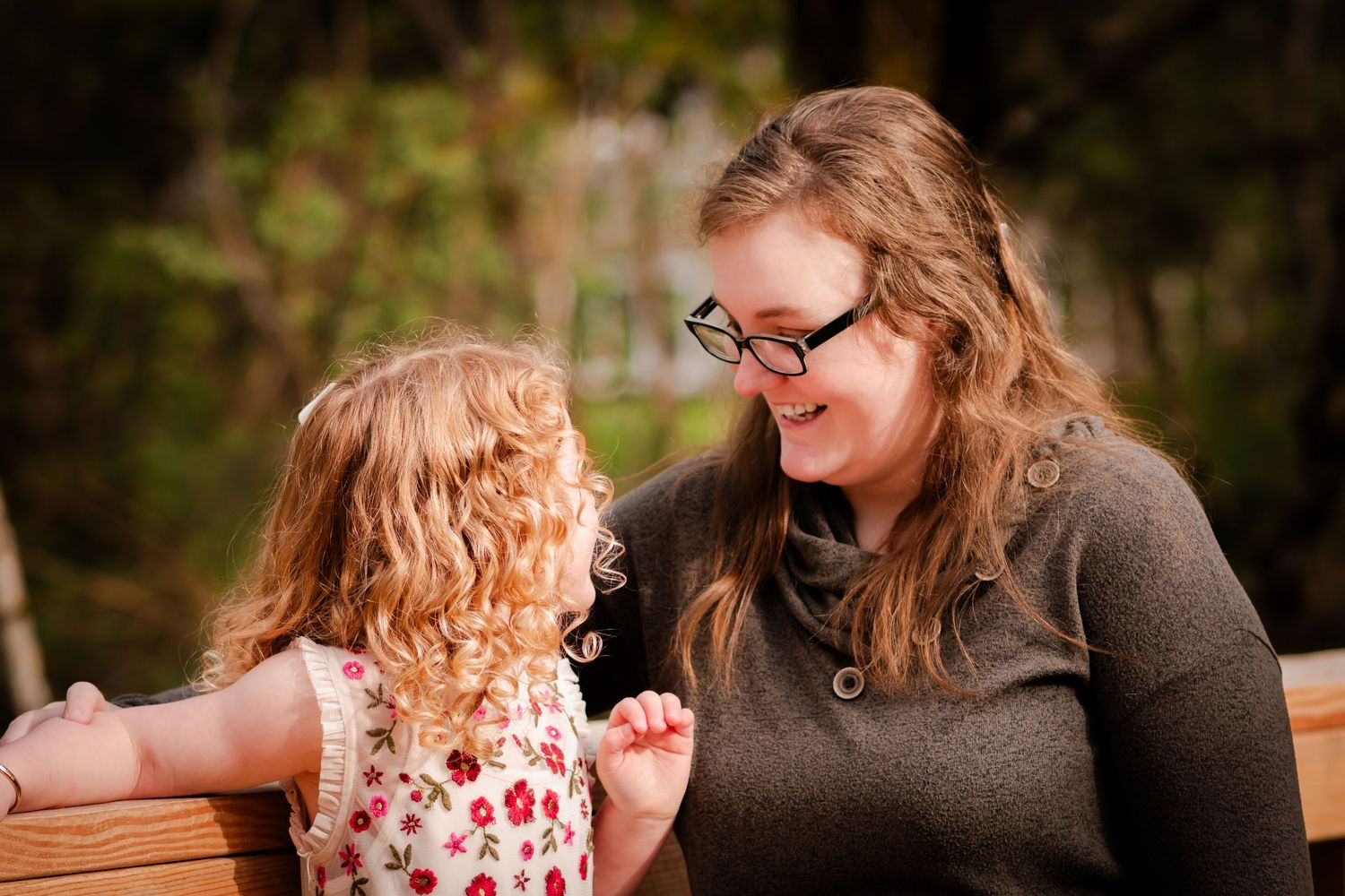 Candid moment of interaction on wooden bench outdoors.