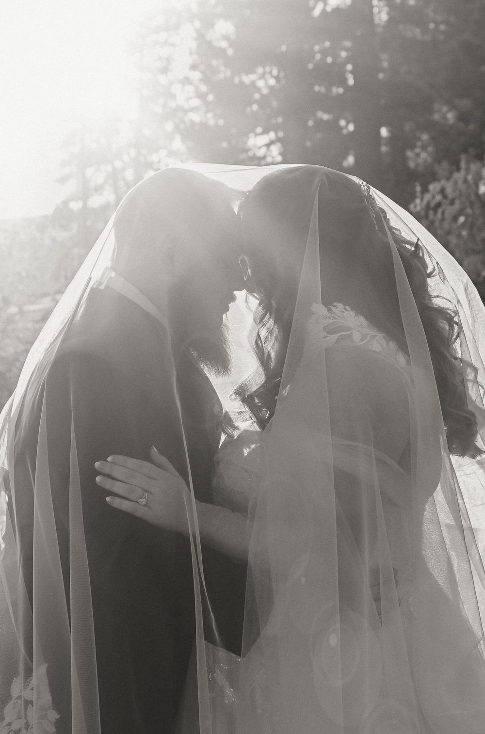 A romantic wedding moment captured in black and white as a couple shares their first kiss under a flowing bridal veil, wedding Tahoe photo