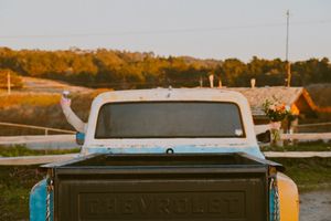 A vintage Chevrolet pickup truck bed viewed at sunset with wooden fence and autumn trees in the background. in Pacifica, California