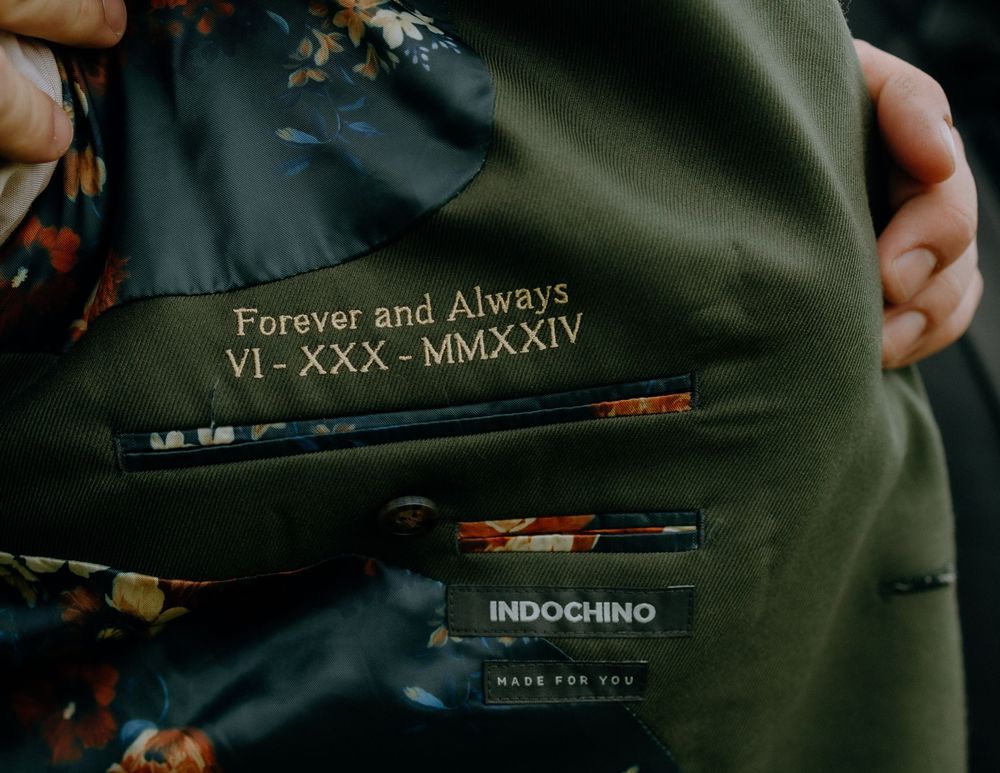Custom embroidered text 'Forever and Always' with Roman numerals on dark fabric.