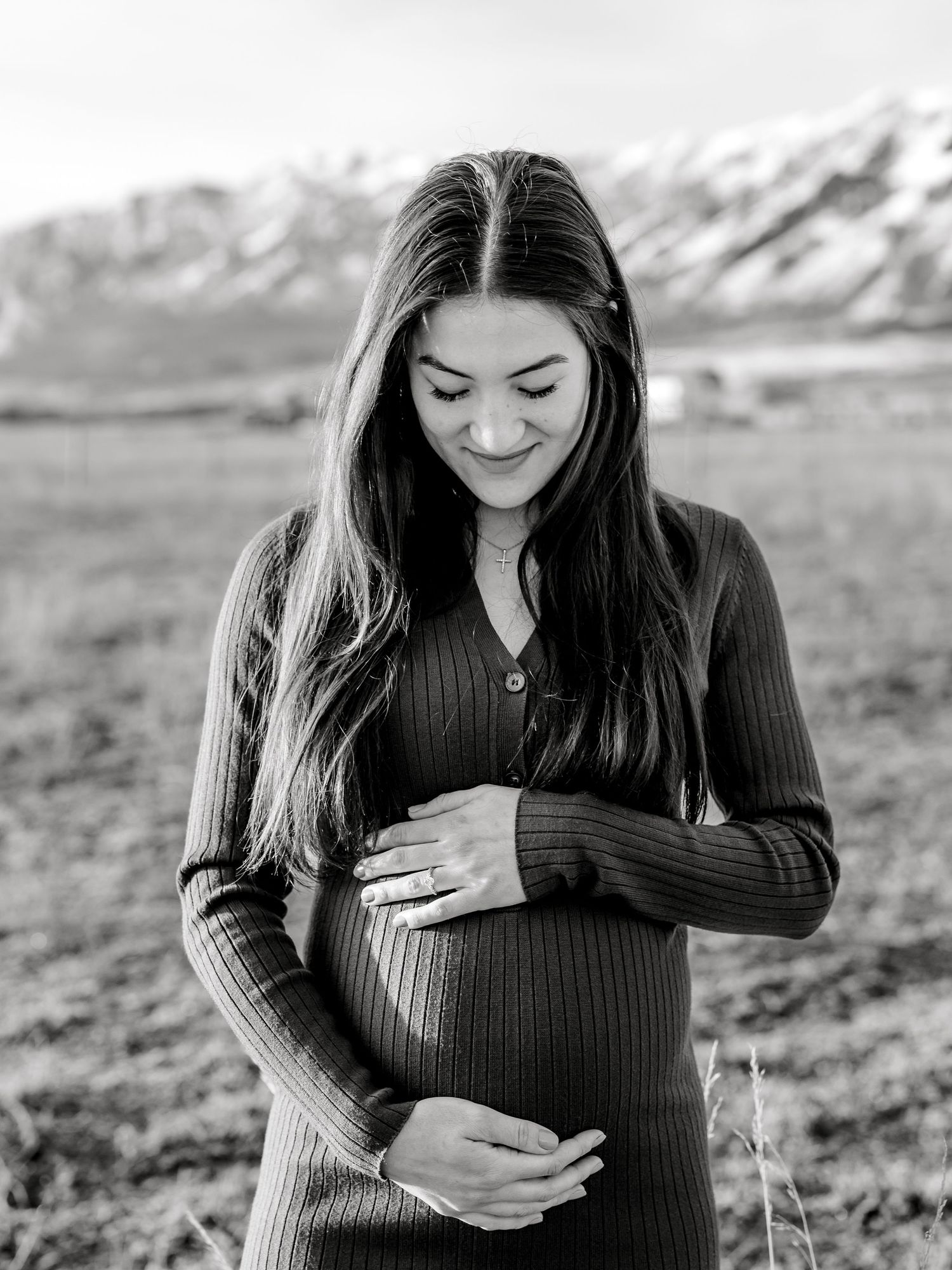 A series of black and white maternity photos showing a woman in a dark sweater cradling her baby bump. Utah Maternity Photos Maternity Photo