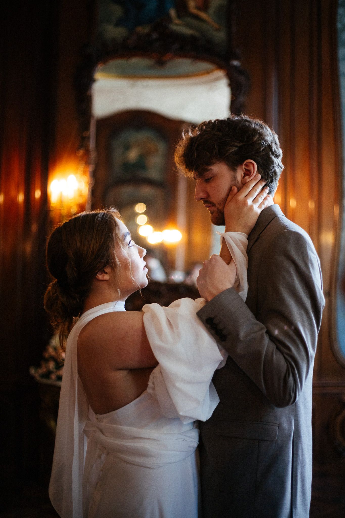 A couple shares an intense intimate look in a dimly lit ballroom in Huis Bartolotti Amsterdam with warm glowing wall sconces.