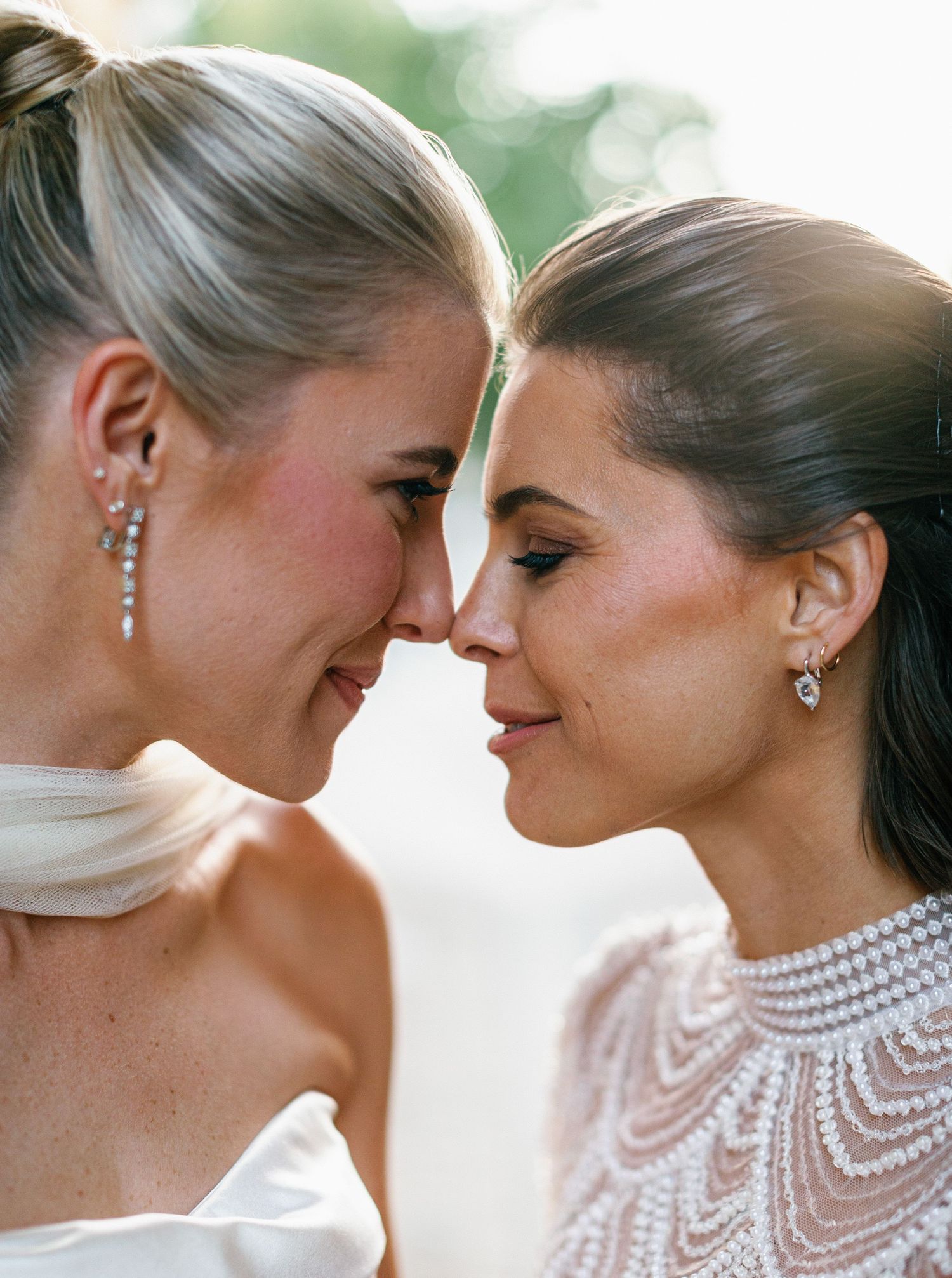Two people in formal wedding attire share an intimate moment against a soft green background.