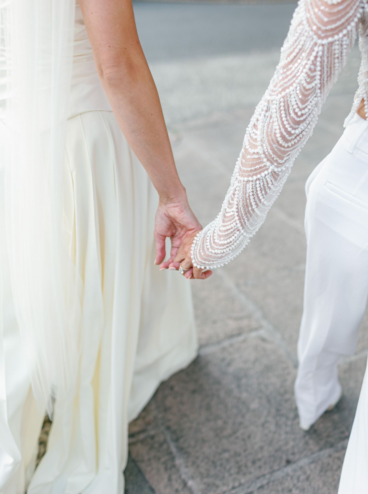Close-up view of a lace sleeve wedding dress detail with delicate scalloped edging and intricate beadwork.