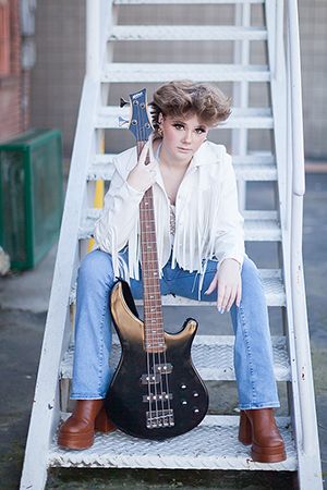 Artistic portrait on white ladder steps with bass guitar and vintage styling.