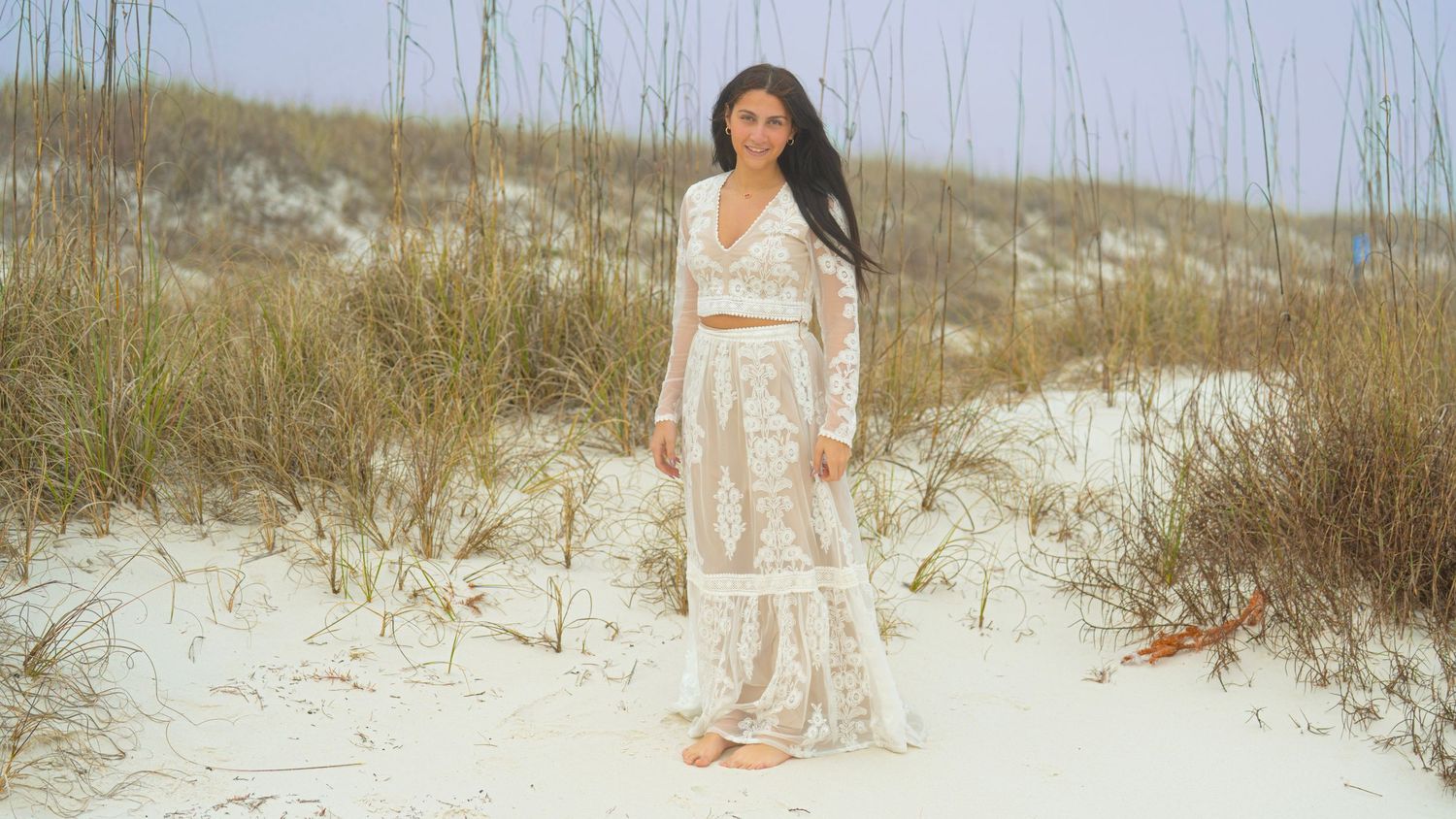 Beachside portrait session with coastal vegetation and sand dunes creating a natural backdrop.