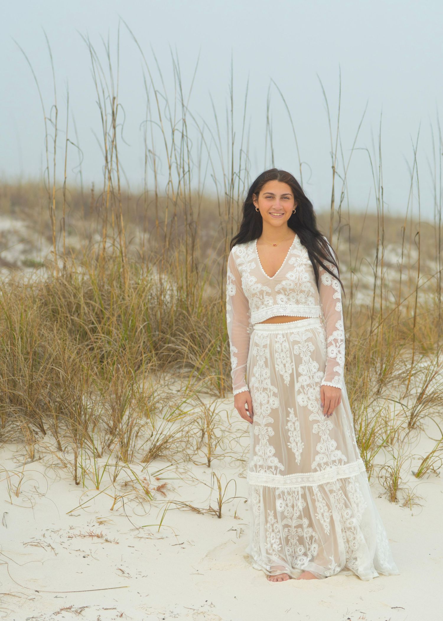 White lace dress photoshoot among beach grass and sand dunes at sunset.