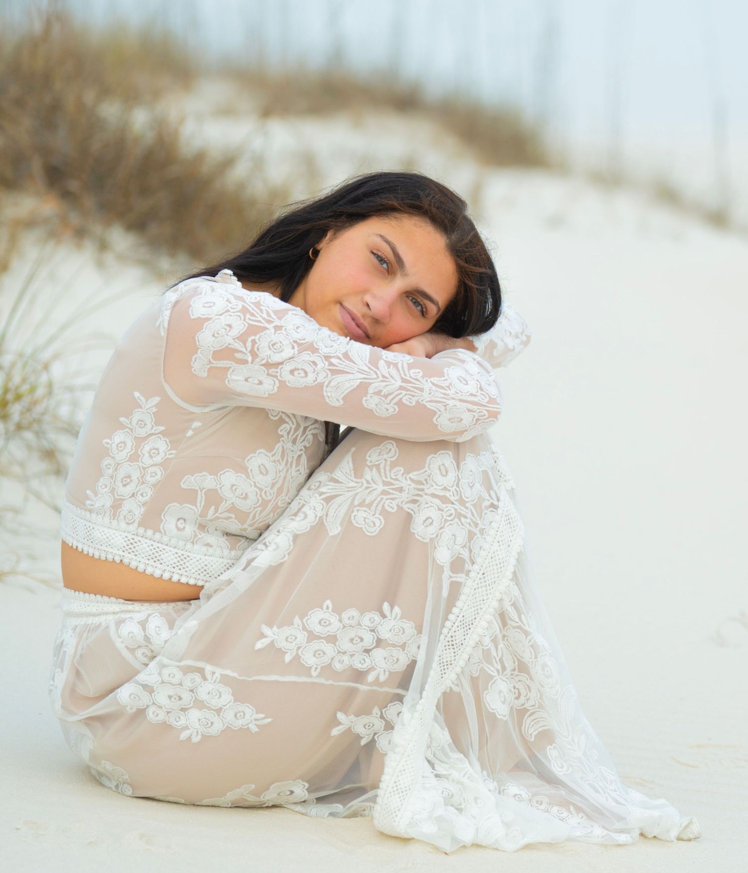 Dreamy beach photography featuring delicate white lace dress against sandy dunes.