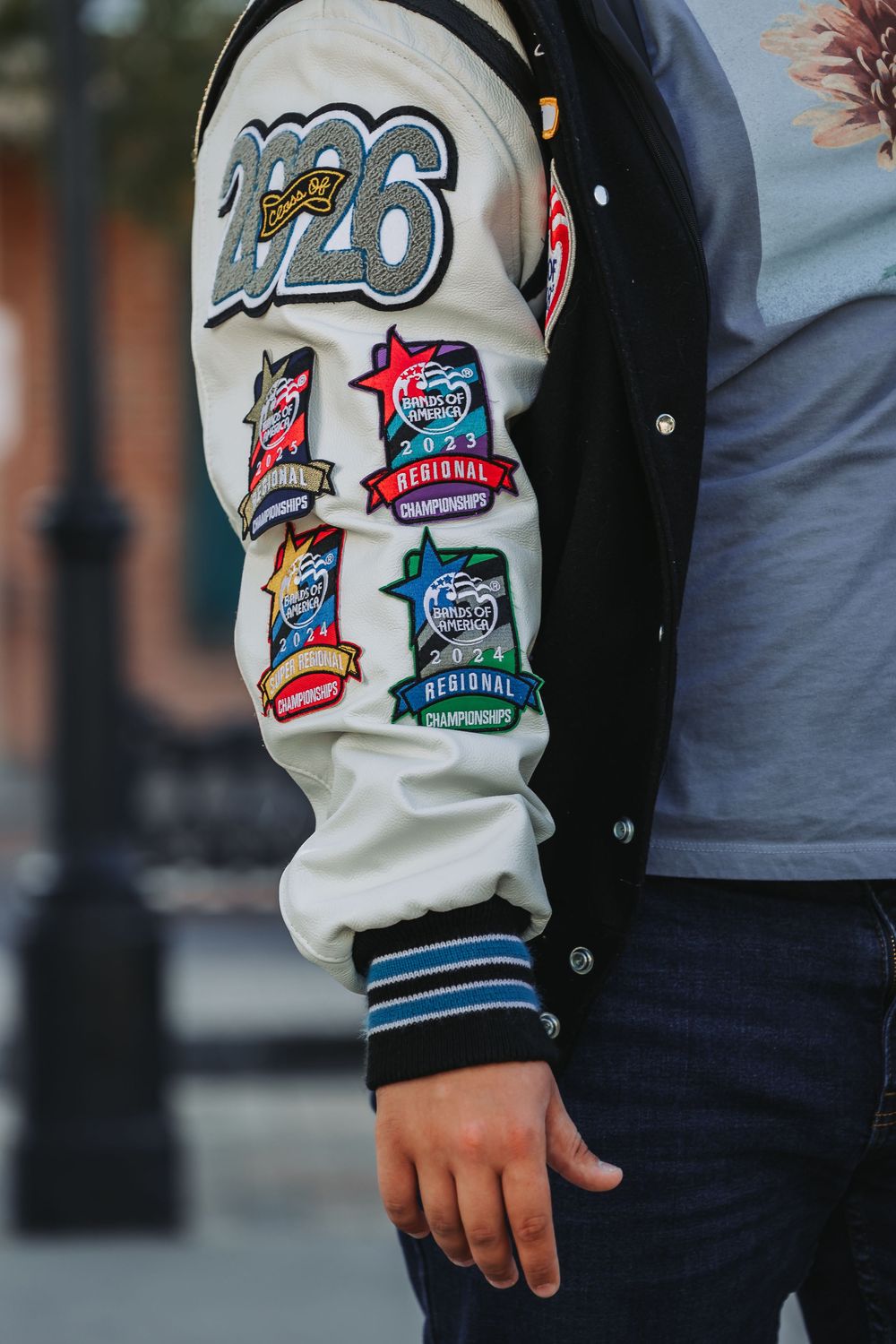 Close-up of a varsity jacket sleeve showing multiple retro-style sports patches and emblems.