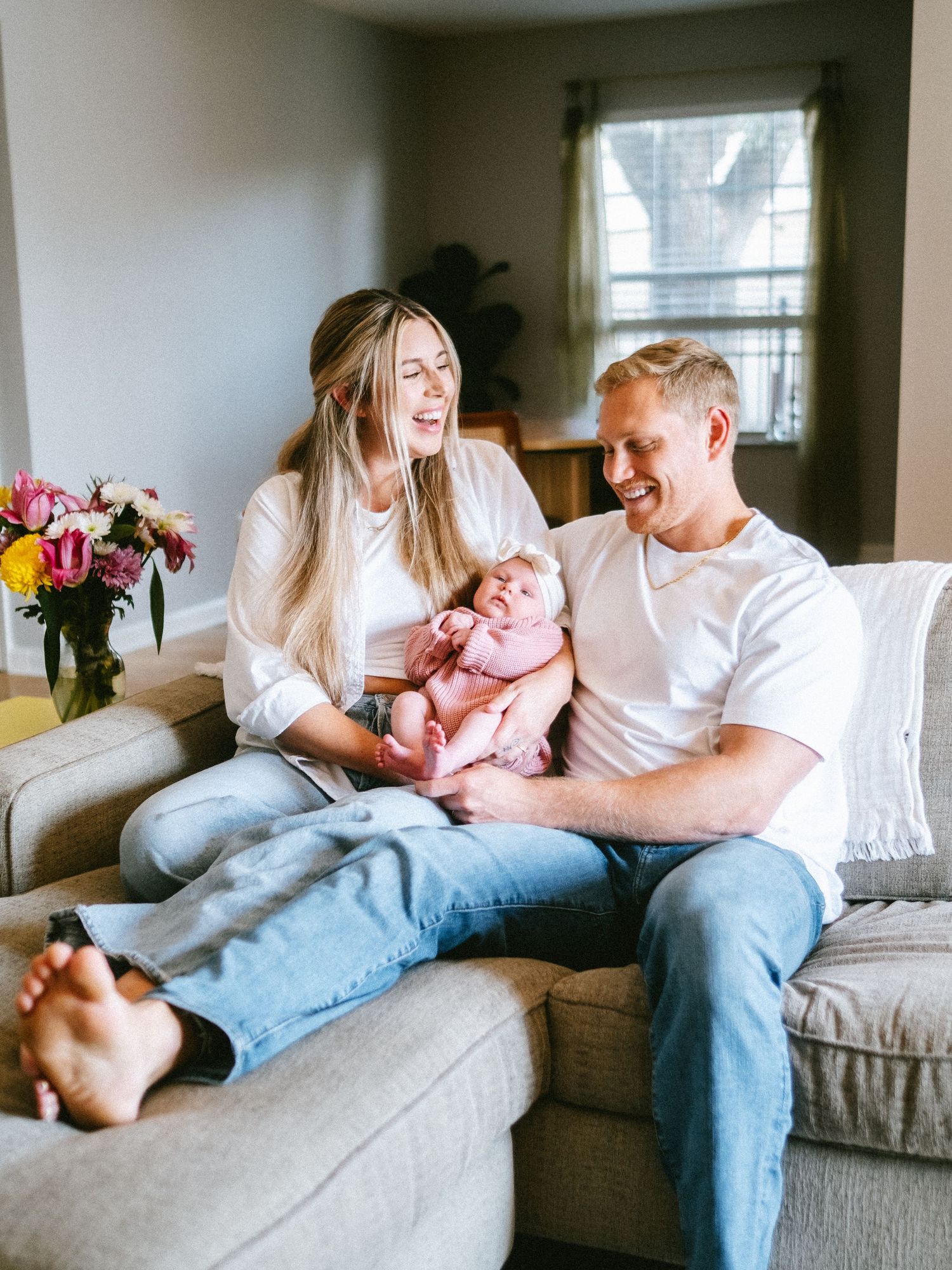 Happy young family with newborn baby relaxing together on a cozy couch at home.