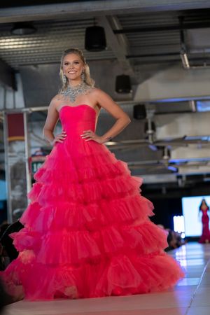 Dramatic hot pink ball gown with tiered ruffles and strapless bodice on catwalk.
