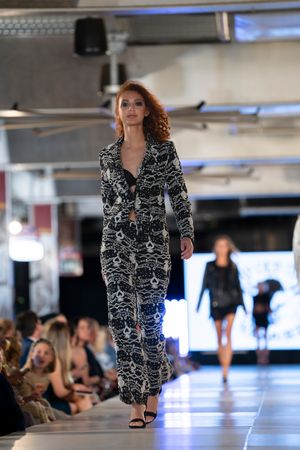 A black and white patterned blazer dress being modeled on an indoor runway.