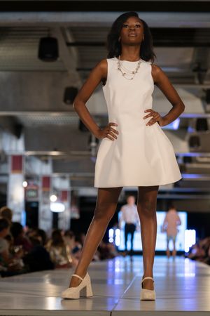 Models walk the runway in white summer dresses during fashion show presentation.