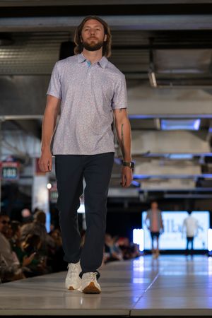 Casual grey polo and dark pants combination presented on fashion runway.