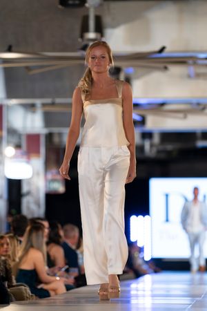 Sleeveless white ensemble displayed on brightly lit indoor catwalk.