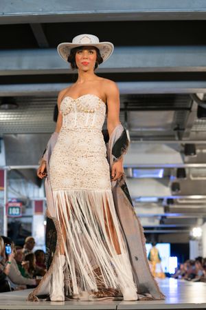 Cream lace dress with metallic fringe details showcased on fashion runway.