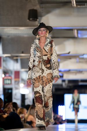 Brown and cream butterfly print ensemble showcased on fashion catwalk.