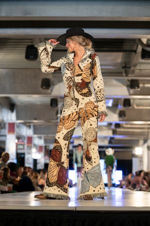 Model presents bohemian-style printed pants and hat ensemble on fashion runway.