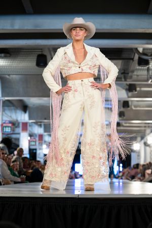 Western-inspired white fringe jacket ensemble displayed on indoor runway.