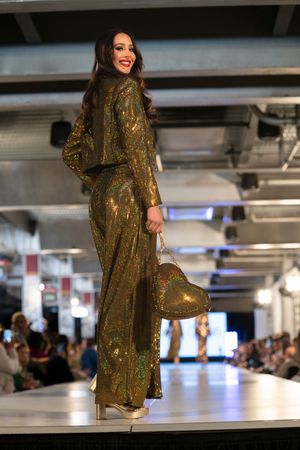 Metallic gold sequined jumpsuit with long sleeves displayed on fashion runway.