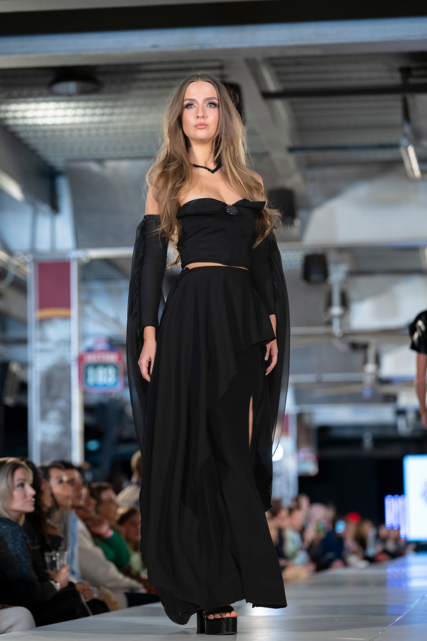 Models showcase black fashion designs on the runway during a contemporary fashion show presentation.